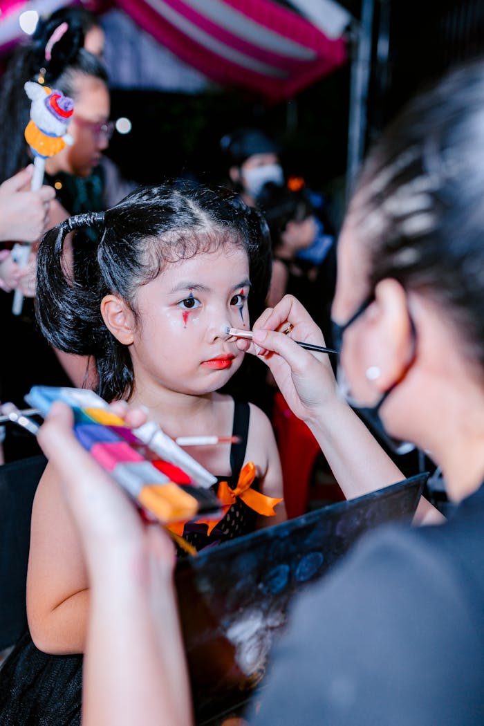 services-04 Young girl having face paint applied by artist during a festive outdoor event.