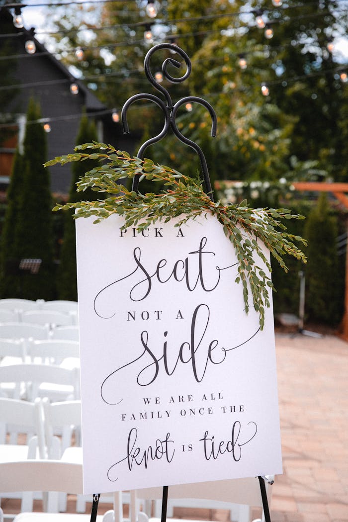 hero-img Charming wedding sign outdoors urging guests to Pick a Seat Not a Side.